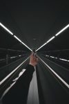 person in black pants walking on escalator